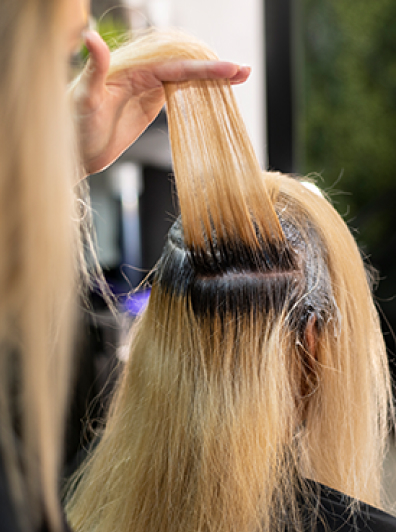 Stylist lifting hair section during color touch-up service