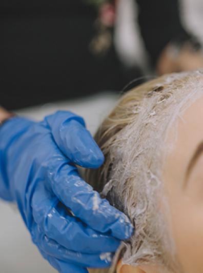 Colorist working color treatment into client's scalp