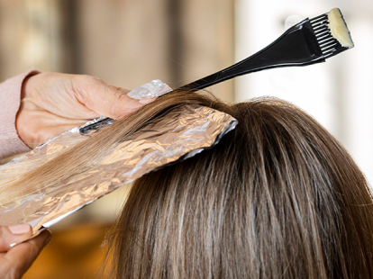 Stylist applying highlight refresh using foil technique