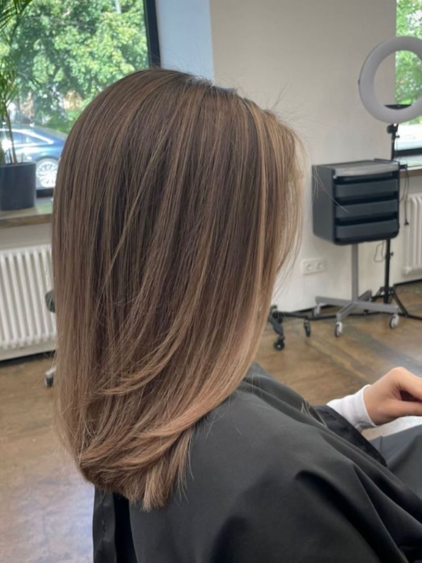 Dimensional partial babylights with fine strands adding depth and movement to medium-length hair.