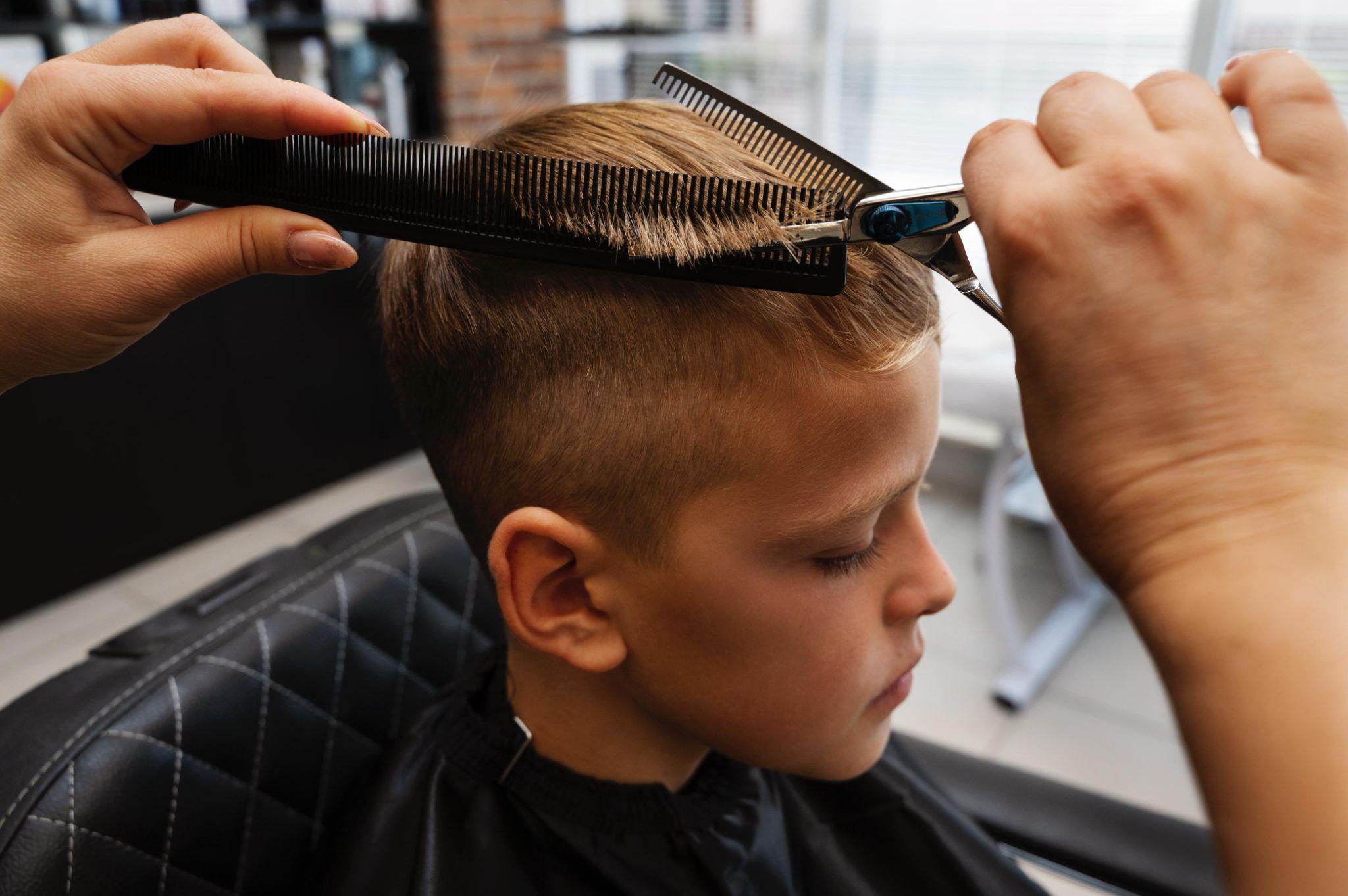 Side view of boy receiving scissor-over-comb on short sides, classic boys haircut with a clean fade