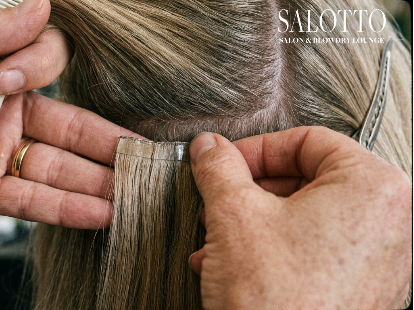 Salotto stylist applies tape-in hair extensions to client in San Diego.