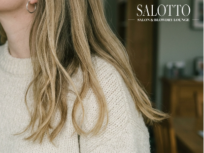 Woman shows long styled hair after tape-in extensions in San Diego salon.